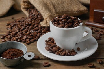 Roasted coffee beans in a cup, coffee beans in a sack, and a coffee grinder