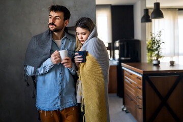 Freezing couple covered with a blanket. Man and a woman wrapped in a warm blanket in a cold room.