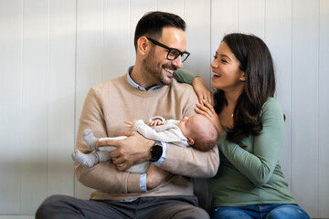 Portrait of parents and newborn baby. Father and mother kiss and hug a beautiful newborn child. . - Powered by Adobe