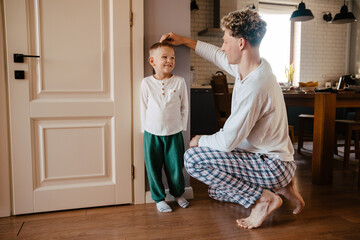 Father measuring height of his son and marking it on wall