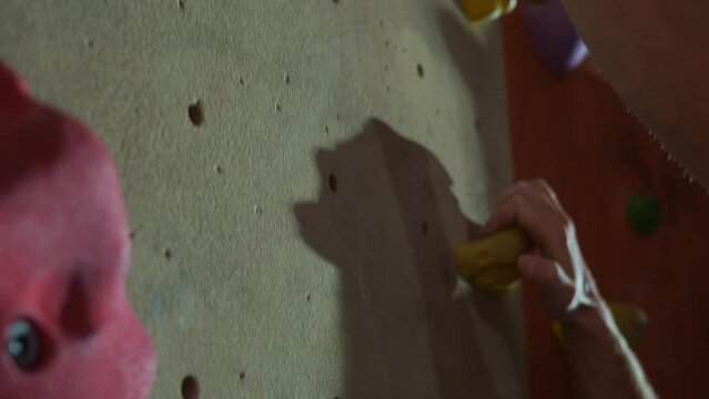 Fitness, extreme sports, bouldering, people and the concept of a healthy lifestyle - close-up of the hands of a young man who trains, does bouldering on a climbing wall indoors. High quality 4k
