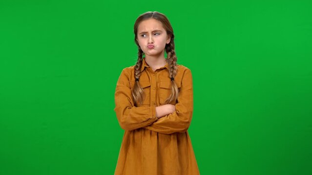 Teen girl pointing at herself looking at camera crossing hands showing tongue out with dissatisfied facial expression. Portrait of cute Caucasian teenager posing on green screen background
