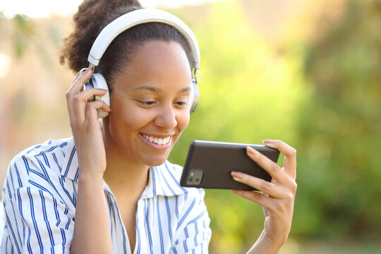 Happy black woman watching videos on phone