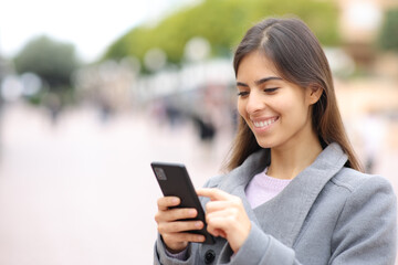 Happy woman using cell phone in winter