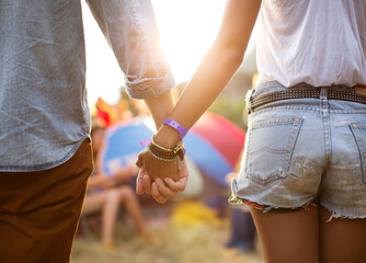 Couple holding hands near tents at music festival