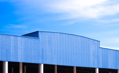 Fototapeta premium Blue Corrugated metal Roof of large Industrial Warehouse Building against blue sky Background in Perspective side view