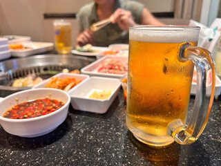 Close up shoot of draft Lager beer in a pint mug on the bar-b-q - Yakiniku Grille table.