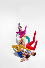 Young girls, ballet dancer in bright tights and bodysuits dancing against grey studio background....