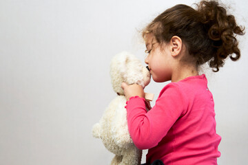 Cute little baby girl kissing teddy bear