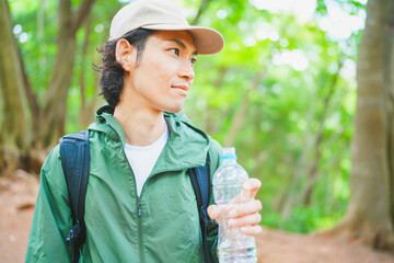 登山で休憩中に水分補給をする若い男性