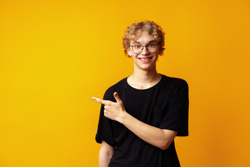 Handsome young man pointing finger to copy space on yellow banner background