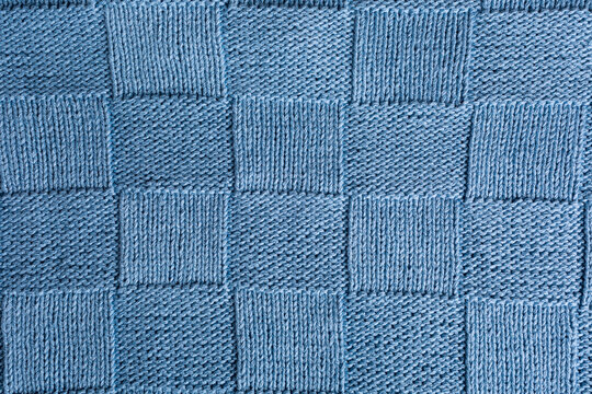 Unusual abstract blue knitted chess pattern background texture. Top view of knitting clothes