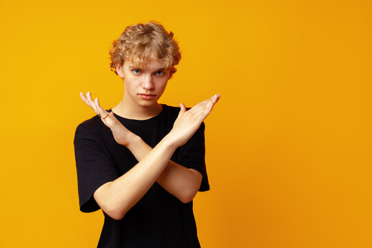 Photo of young strict man showing arms denial symbol against yellow background
