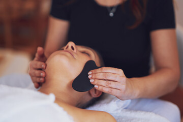 Obraz na płótnie Canvas Brunette woman having a stone massage on face