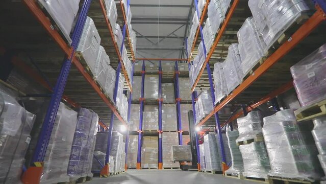 The forklift is driving through the warehouse of the factory. Modern warehouse. Large warehouse in the factory. Warehouse work