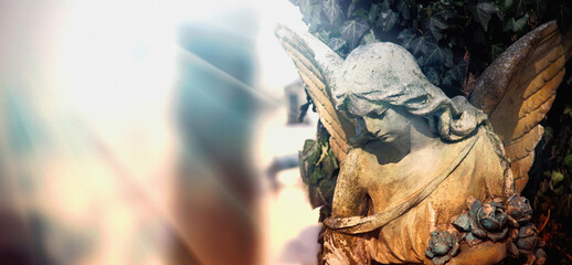 Sad angel on a cemetery. Ancient statue. Copy space.