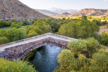 Aerial view of old Dadal bridge over Arpa river on autumn evening. Yeghegnadzor, Vayots Dzor Province, Armenia.