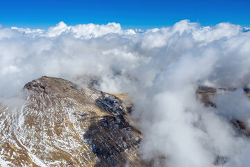 Aerial view of Aragats Eastern peak surrounded by clouds on sunny autumn day. Armenia.