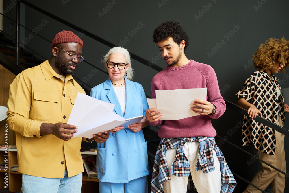 Aufkleber Group of intercultural economists discussing financial papers at working meeting while standing in front of camera against staircase