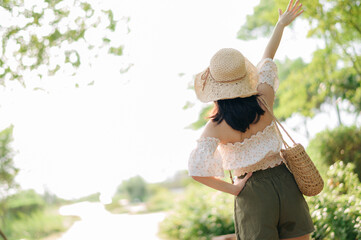 Portrait of asian young woman traveler with weaving hat and basket and a camera on green public park nature background. Journey trip lifestyle, world travel explorer or Asia summer tourism concept.