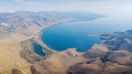 Panoramic aerial view of Sevan lake and Artanish village from above Mount Artanish on sunny autumn day. Gegharkunik Province, Armenia.