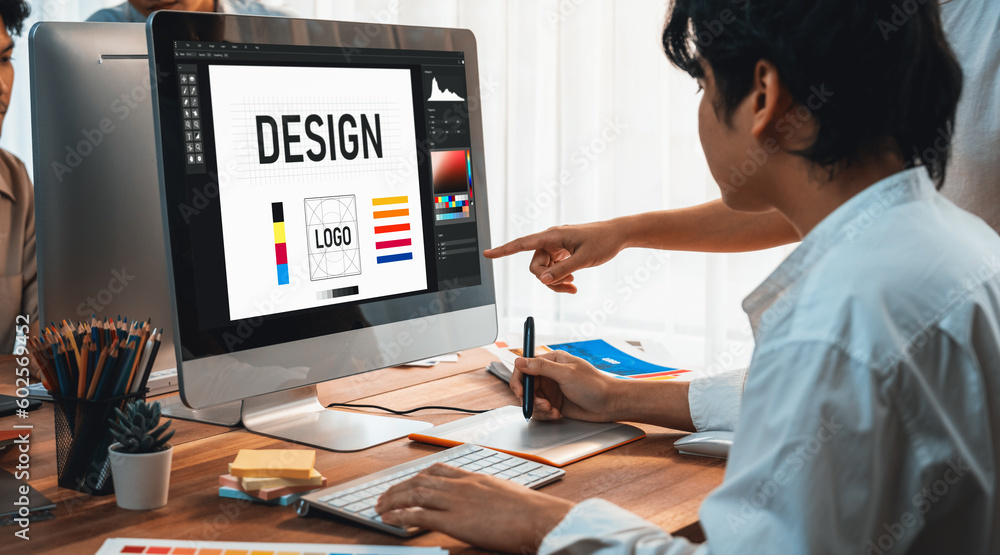 Poster Graphic designer work on computer laptop and with graphic drawing pen while brainstorming unique design with professional graphic team in modern digital studio workplace. Panorama shot. Scrutinize