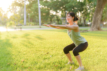 Female jogger. Fit young Asian woman with green sportswear squatting in park before running and...