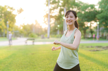 Female jogger. Fit young Asian woman with green sportswear stretching muscle in park before running and enjoying a healthy outdoor. Fitness runner girl in public park. Wellness being concept