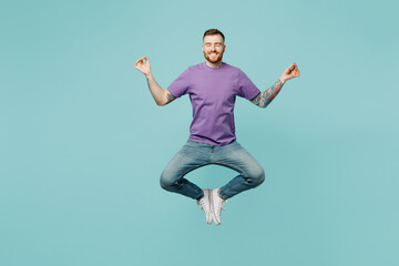 Fototapeta na wymiar Full body young man he wears purple t-shirt jump high hold spreading hands in yoga om aum gesture relax meditate try to calm down isolated on plain pastel light blue cyan background studio portrait.