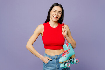 Young smiling happy latin woman she wearing red casual clothes hold rollers looking camera wink blink eye isolated on plain pastel purple background studio portrait. Summer lifestyle leisure concept.