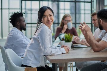 Multiethnic business partners having meeting at table with laptops in modern office