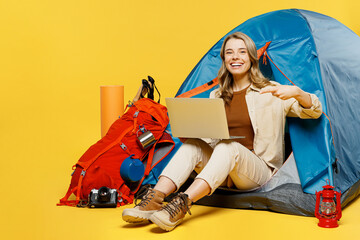 Full body young IT woman sit near bag with stuff tent hold pont finger on laptop pc computer...