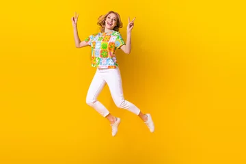 Zelfklevend Fotobehang Full length photo of excited cool lady wear flower print t-shirt jumping showing v-signs empty space isolated yellow color background © deagreez