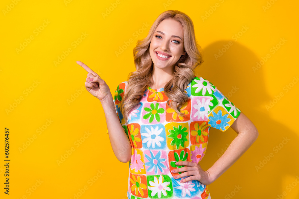 Sticker Photo of pretty young girl showing novelty product empty space directing finger wear print shirt isolated yellow color background