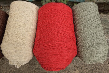 three large colored bobbins of woolen thread lie on the table