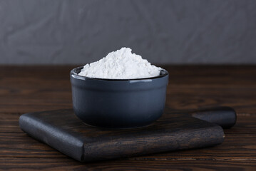 White powdered tapioca starch in a bowl on a wooden board, dry cassava root.