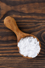 White powdered tapioca starch in a wooden spoon, dry cassava root.