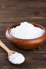 Tapioca starch in a wooden bowl and spoon, dry cassava root.