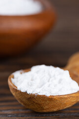 Powdered tapioca starch in a wooden spoon, dry cassava root.