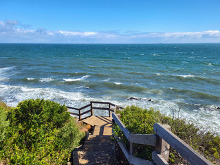 View from the boardwalk at Mornington overlooking Port Phillip Bay with rough seas and blue skies.