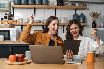 Two happy teenage girls Glad to raise your hand to receive message on tablet resting in kitchen