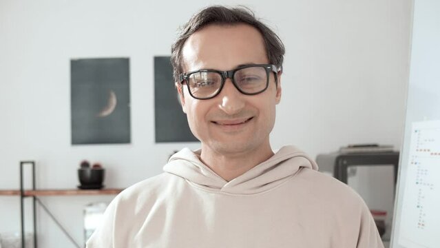 Motivational business footage. Portrait of a successful adult man in glasses who openly smiles against the backdrop of an informal office. Family business. Business training. Individual entrepreneur