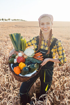 Woman carrying basket with healthy and locally produced vegetables on a grain field