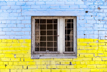 Fototapeta na wymiar pattern explosion damaged blue yellow house wall with window in Ukraine