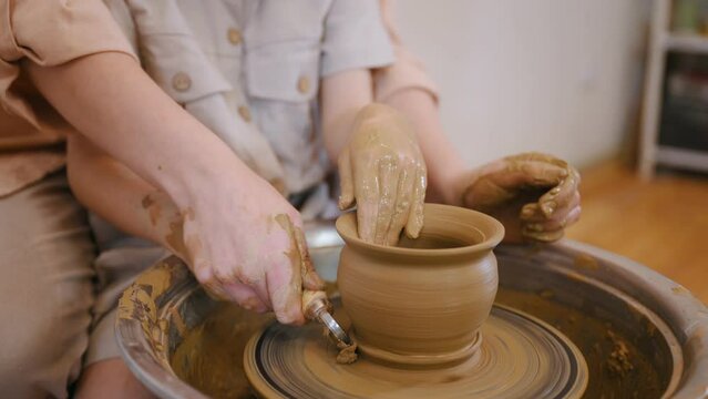 Close up view, making shape. Mother with little girl doing pottery practice.