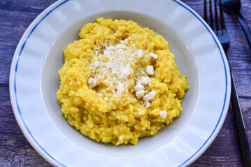  Italian risotto milanese  with parmesan cheese and fresh basil on rustic background