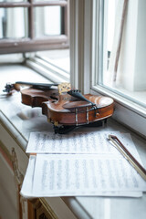 violin near musical notes partition on windowsill