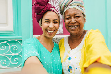 Happy african mother and daughter taking selfie in front of traditional house in north africa -...