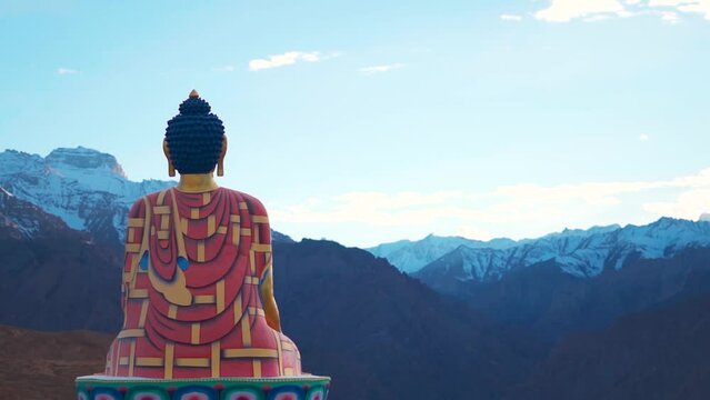 Rear view shot of Langza Buddha statue in front of the Snow covered Himalayan mountains at Langza village in Spiti Valley, Himachal Pradesh, India. Statue of Buddha facing the snowy Himalayas in India