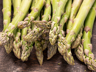 Close up of fresh and raw green asparagus spears on old wooden board
